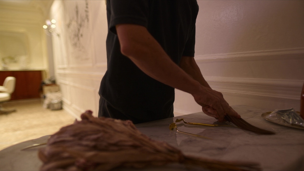 A stylist's hands working on bridal hair in soft natural light, brass tools nearby
